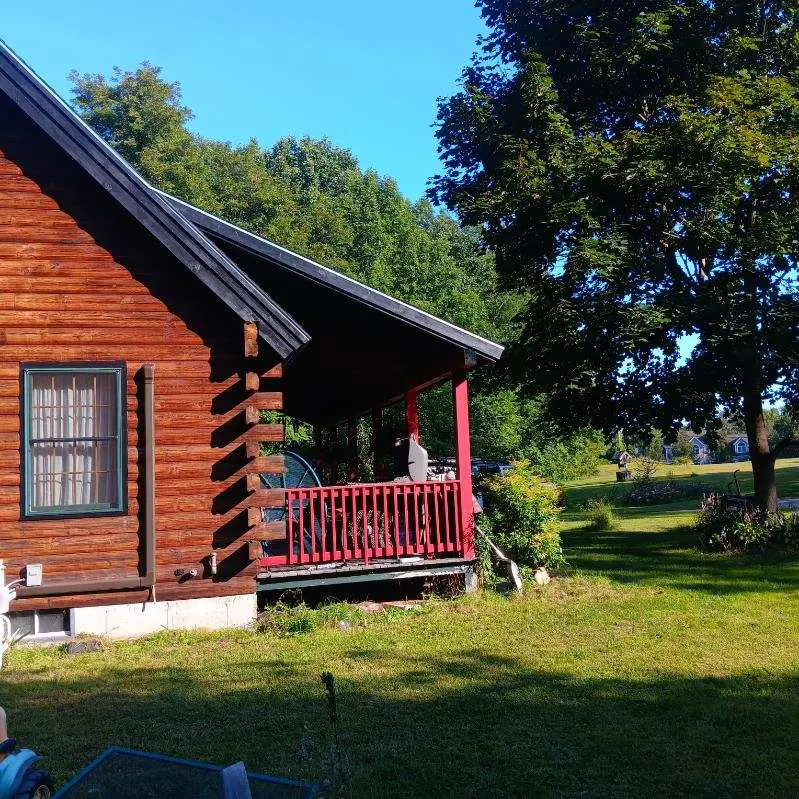 Rustic log cabin exterior showcasing freshly painted wood siding and porch accents enhancing natural charm, completed by Zellers Painting & Contracting.