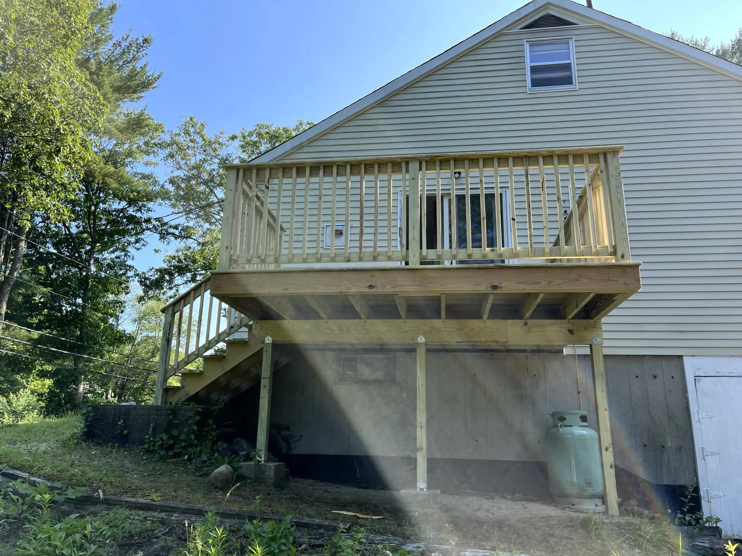 Residential exterior project showcasing a newly built wood deck and staircase ready for finishing, completed as part of a professional home improvement service by Zellers Painting & Contracting.