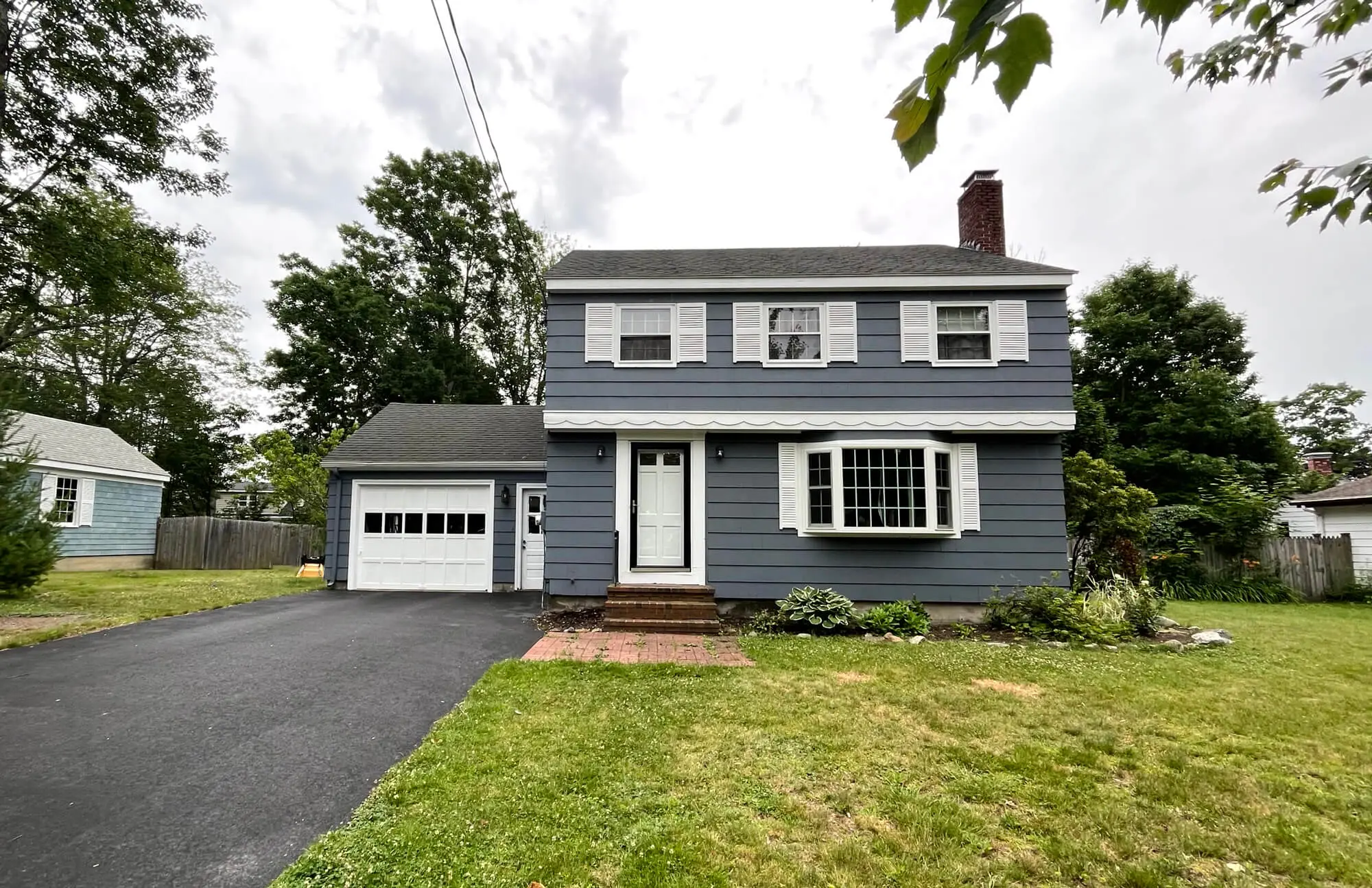 PAINTING SERVICES IN PORTLAND, ME showcasing a freshly painted gray two-story home with crisp white trim and enhanced curb appeal completed by Zellers Painting & Contractin