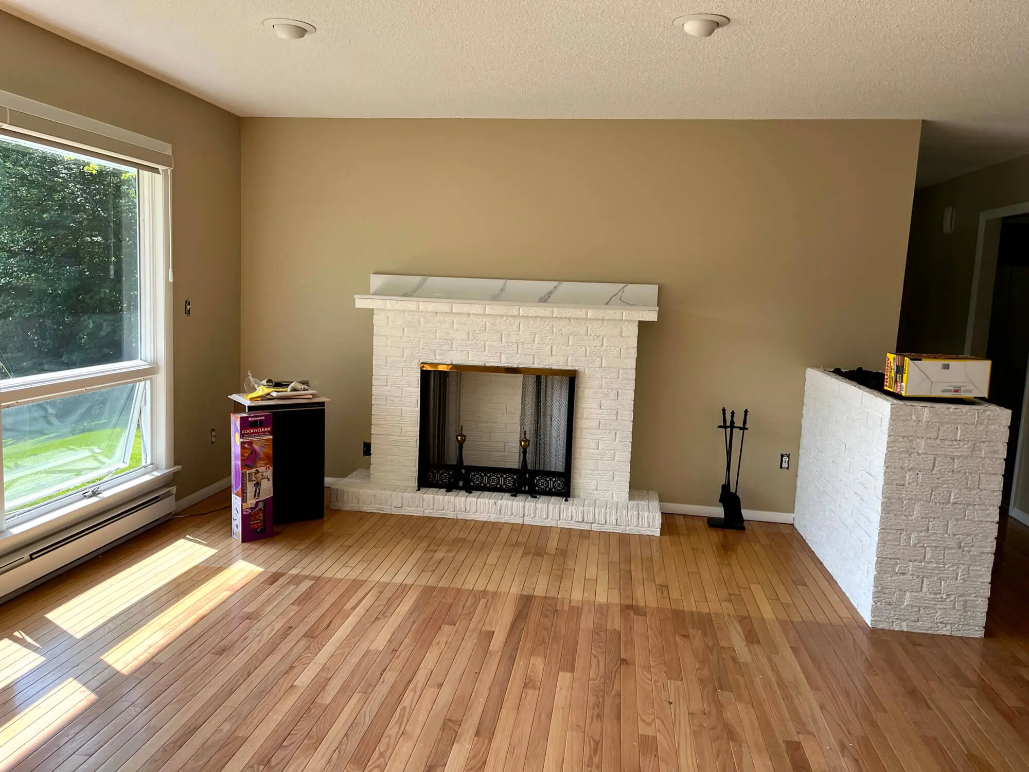 Warm, professionally painted living room interior with smooth beige walls, crisp white brick fireplace, and a clean, modern finish completed by Zellers Painting & Contracting.